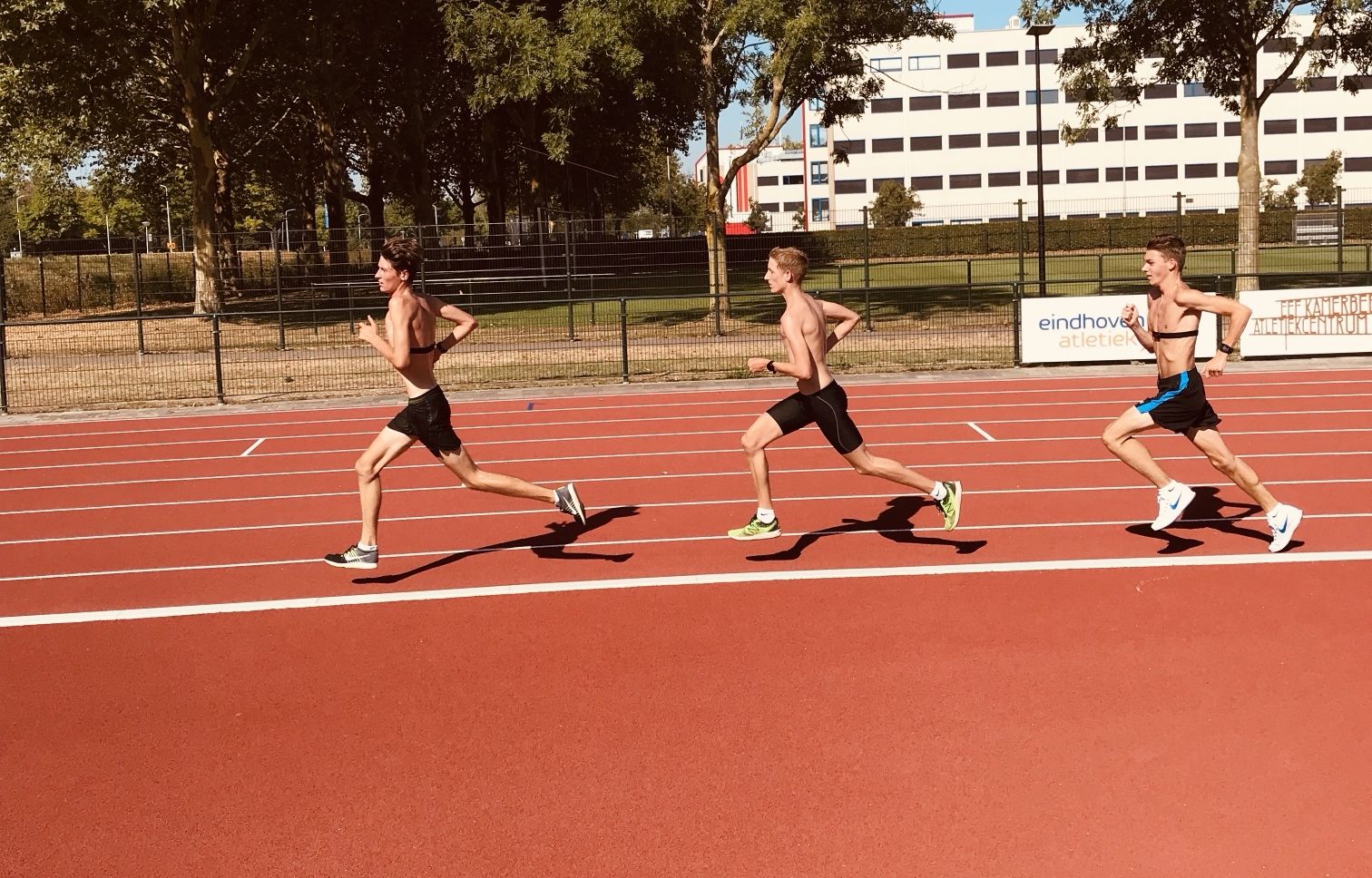 Three runners in a line on the athletics track